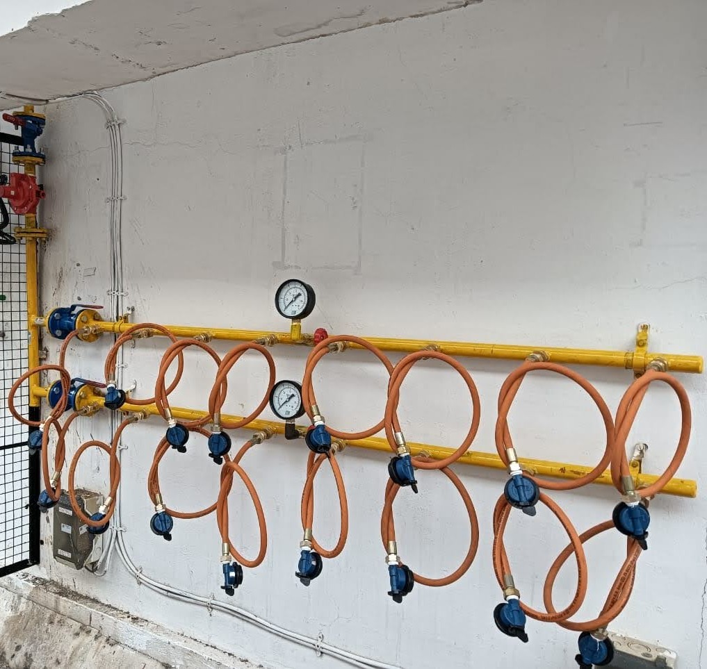 Wall mounted LPG manifold with yellow piping, gauges and hoses installed by IGNITE LPG TRACK